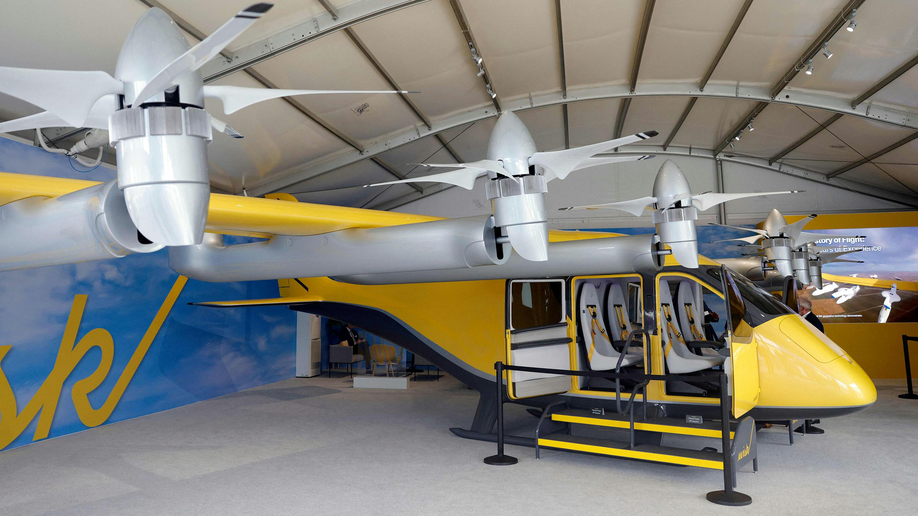 A small yellow aircraft with several propellers (an electric air-taxi)