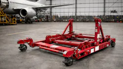 A red engine stand in a hangar with an airplane in the background