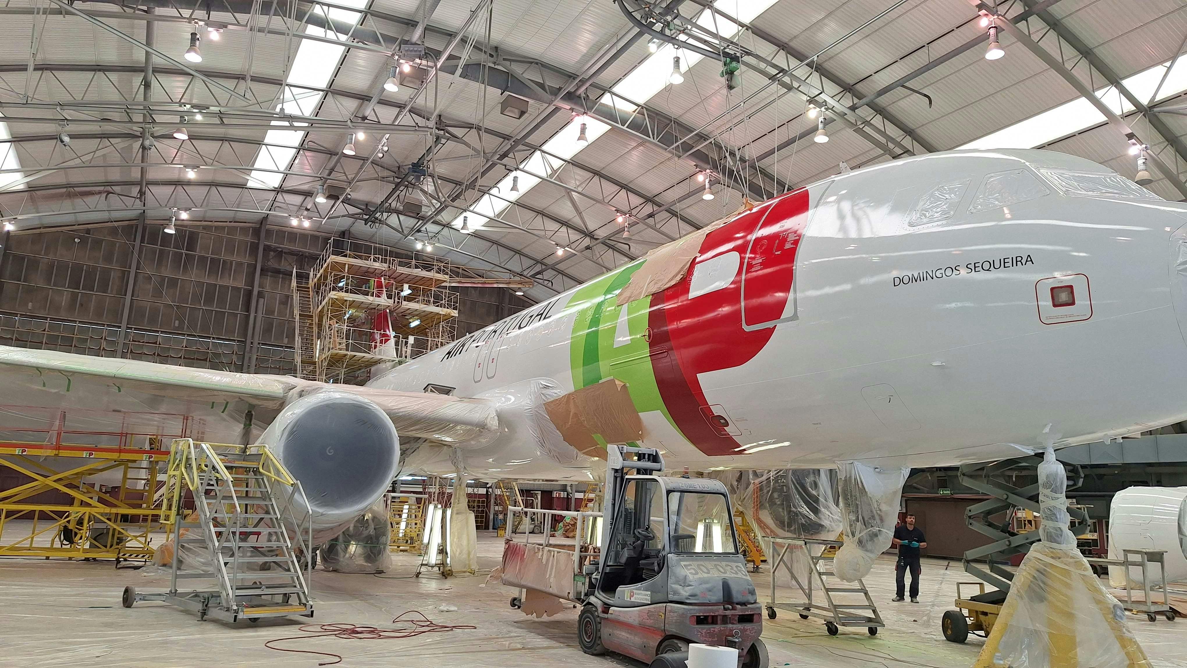 An airplane parked inside of a hangar with utility stairs next to it
