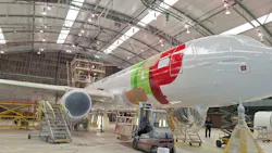An airplane parked inside of a hangar with utility stairs next to it