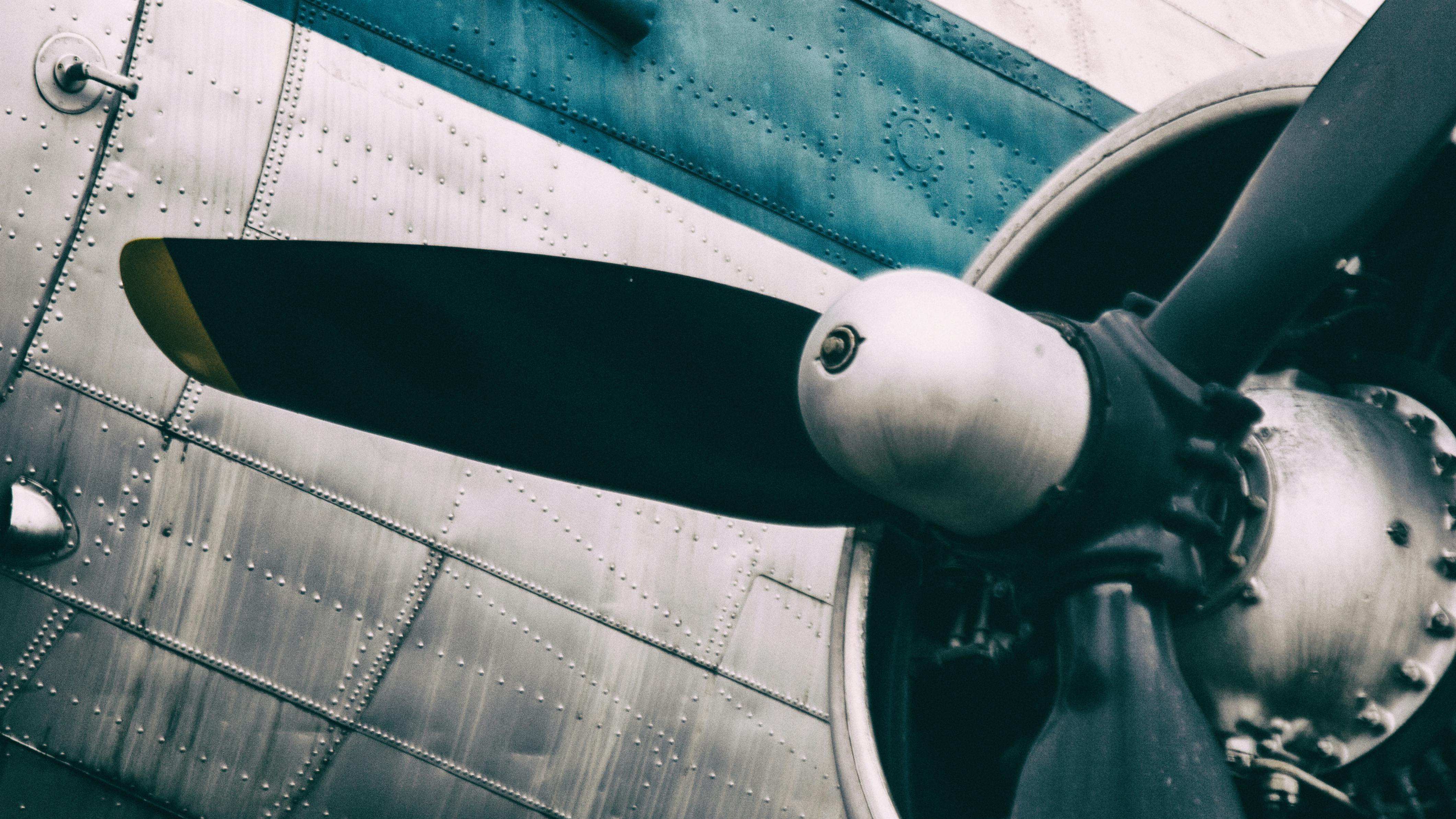 A zoomed-in photograph of an airplane engine propeller, showing signs of corrosion and wear