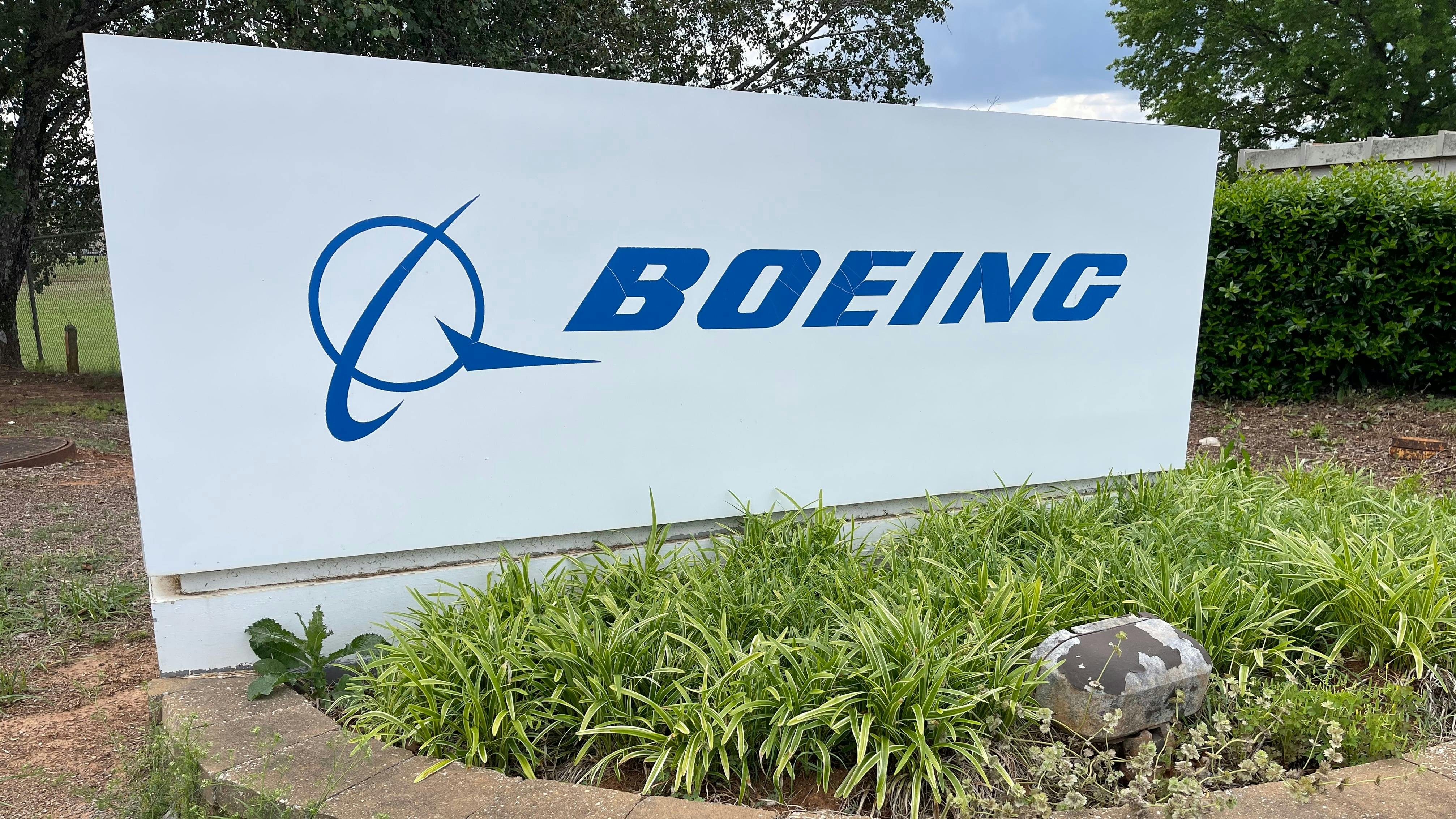 A white sign with a blue graphic and text that reads: BOEING