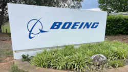 A white sign with a blue graphic and text that reads: BOEING