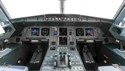 An avionics dashboard inside an airplane cockpit, with dials, buttons, switches and screens