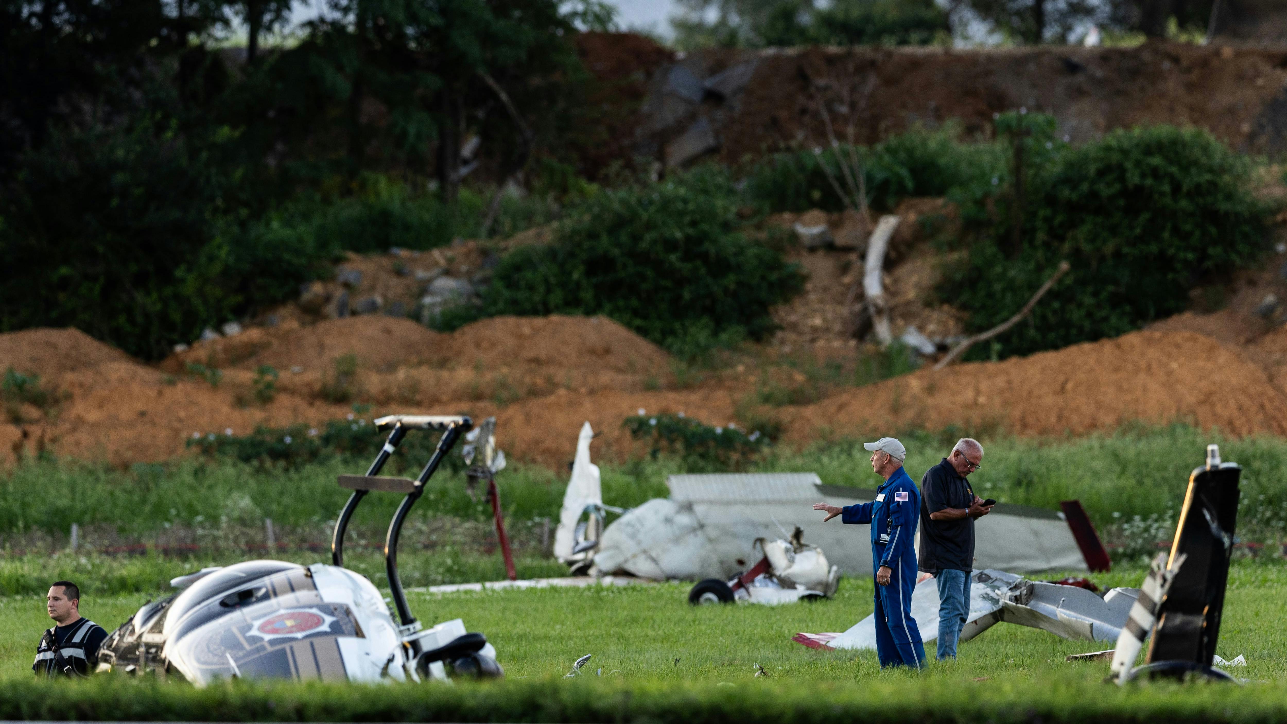People standing in a grassy area among wreckage from an aircraft crash