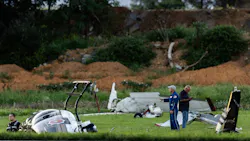 People standing in a grassy area among wreckage from an aircraft crash