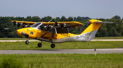 A small yellow aircraft with 'ELECTRA' printed on the side flying near the ground on a runway