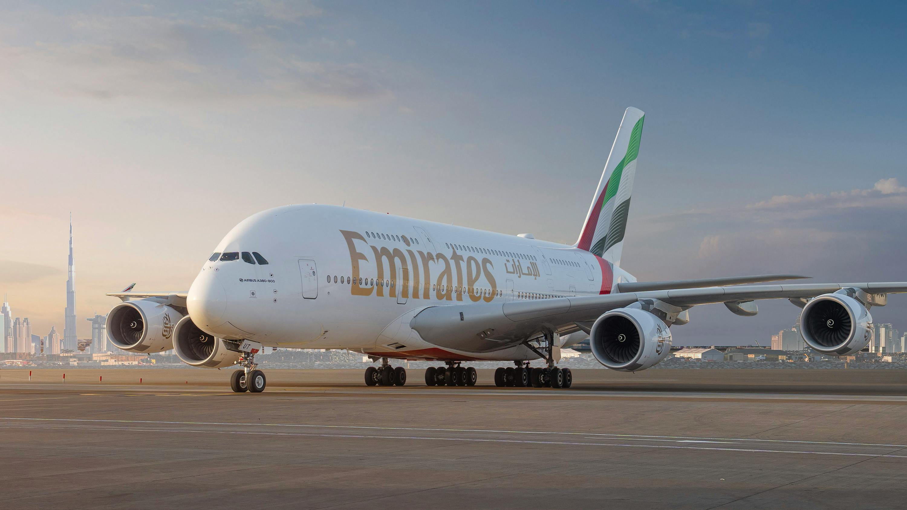A large airplane parked on a tarmac with red and green accents on the tail and text that reads 'Emirates'
