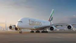 A large airplane parked on a tarmac with red and green accents on the tail and text that reads 'Emirates'