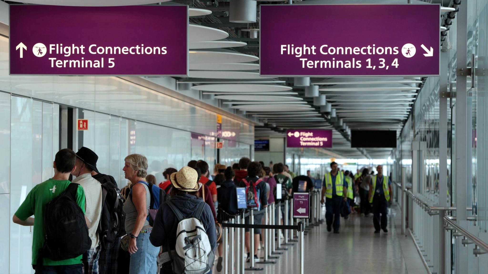 People stand in a hallway that connects terminal 5 to other terminals on Heathrow Airport.