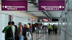 People stand in a hallway that connects terminal 5 to other terminals on Heathrow Airport.