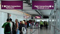 People stand in a hallway that connects terminal 5 to other terminals on Heathrow Airport.
