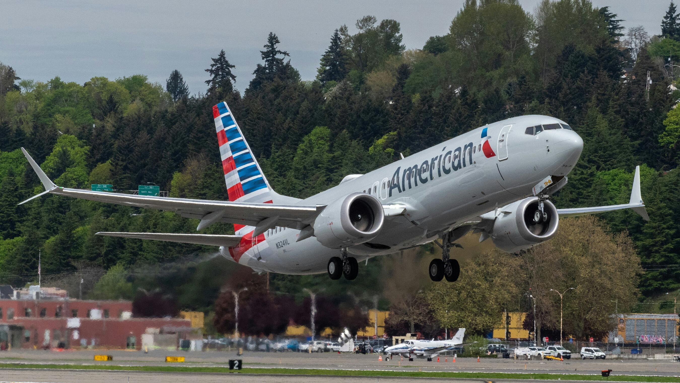 A white airplane with a red-and-blue tail text on the side that reads: American