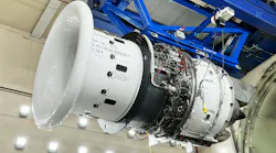 An aircraft engine being held up in the air by a piece of blue metal machinery