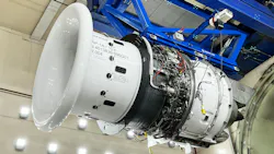 An aircraft engine being held up in the air by a piece of blue metal machinery