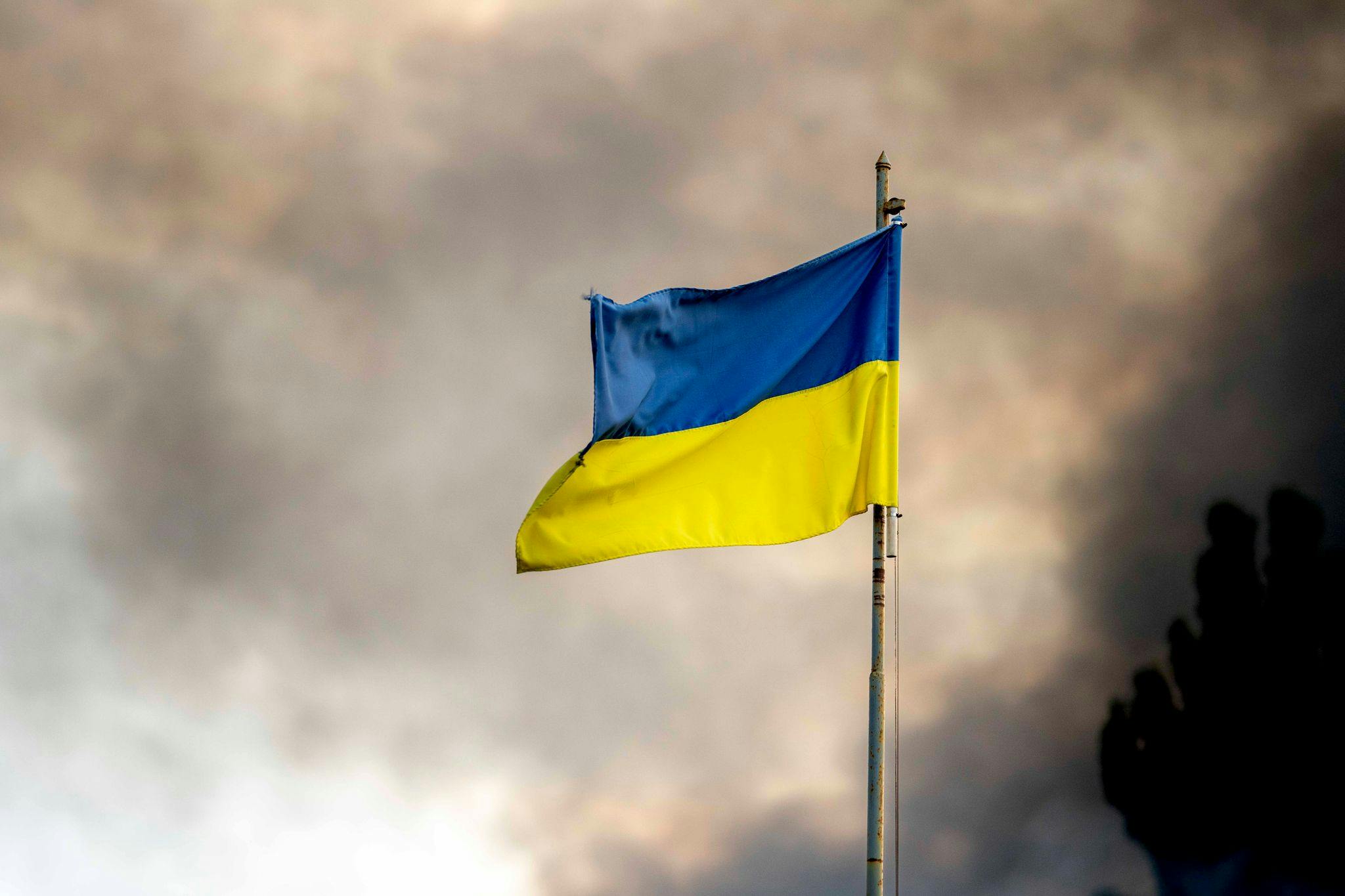 A Ukrainian flag seen in front of thick smoke which is rising from fire over Kyiv after Russian missile attacks on Ukraine.