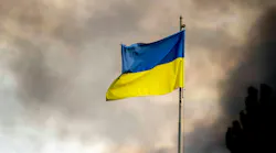 A Ukrainian flag seen in front of thick smoke which is rising from fire over Kyiv after Russian missile attacks on Ukraine.