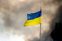 A Ukrainian flag seen in front of thick smoke which is rising from fire over Kyiv after Russian missile attacks on Ukraine.