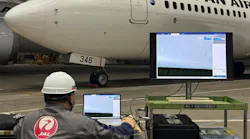 A technician sitting at a computer and viewing an image of an airplane being inspected