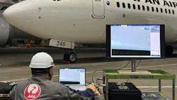 A technician sitting at a computer and viewing an image of an airplane being inspected