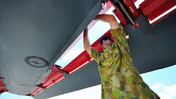 A technician wearing military fatigues standing under the wing of an airplane