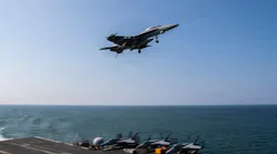 An aircraft flying above an aircraft carrier floating in the sea