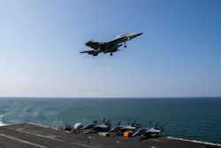 An aircraft flying above an aircraft carrier floating in the sea