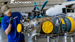 A technician wearing a blue polo working on an airplane engine, with the word 'BLACKHAWK' printed at the top of the photograph