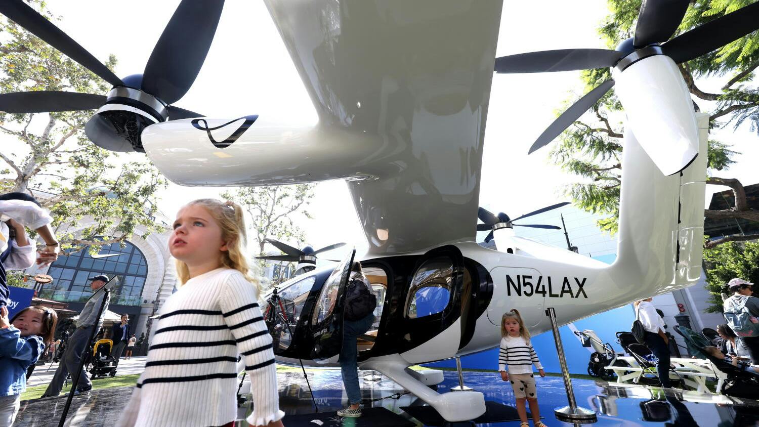 LOS ANGELES, CA - - SEPTEMBER 26, 2024 - Cleo Sinnott, 3, left, and her sister Maja, 2, from Sydney, Australia, visit with a flying taxi created by Joby Aviation at The Grove in the Fairfax District in Los Angles on September 25, 2024. Joby Aviation, Inc., is one of a handful of companies racing to be the first to make flying taxis a reality in Los Angeles. The California-based transportation company has developed the all-electric, vertical take-off and landing air taxi which it intends to operate as part of a fast, quiet, and convenient service in cities around the world.