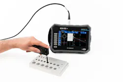 A hand placing a sensor attached to a tablet against a piece of metal