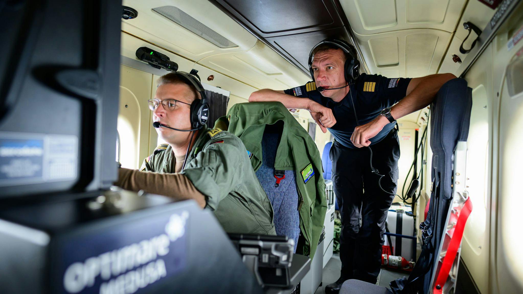 Kevin (left), a German military operator, and Benedikt Spangardt from Germany's Maritime Emergency Response Centre monitor a ship over the North Sea from a twin-engine propeller aircraft.